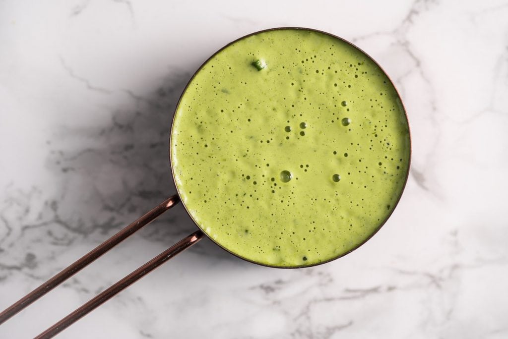 Aderezo verde de mayonesa para ensaladas en una taza de medidas.