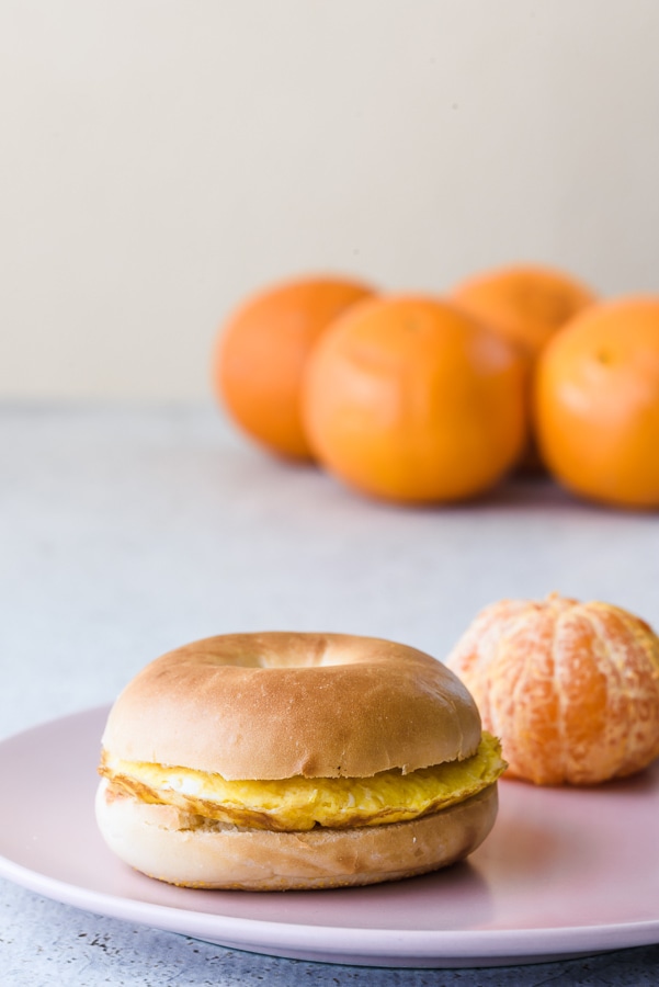 Mini bagel de huevo y mandarina en un plato.