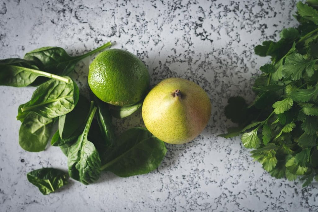 Spinach, lime, pear, and cilantro on the table.