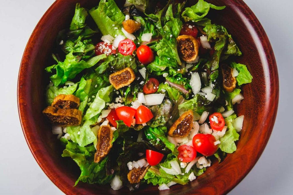 Ensalada de lechuga verde, tomates y higos secos.