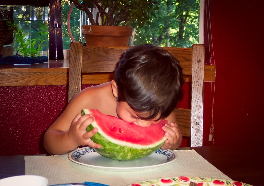 Niño come sandia solo.