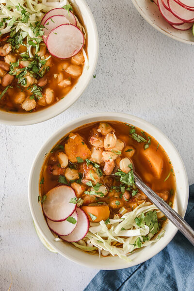 Pozole rojo con repollo, rábanos y cilantro.