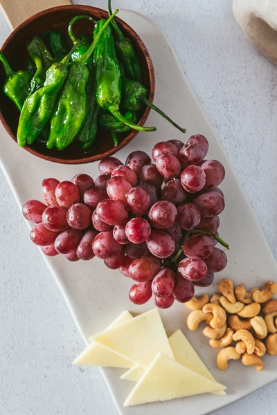 Grapes appetizer with shishito peppers, cashews, and cheese.